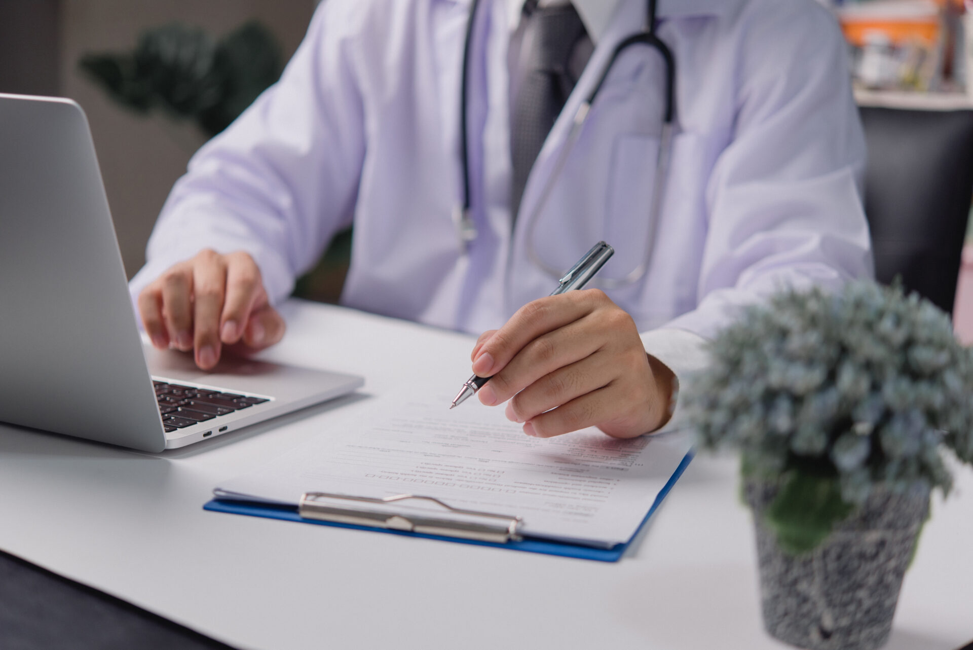 form being filled by doctor while working on laptop